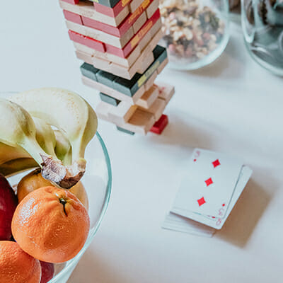 a fruit bowl with clementines and bananas sits beside a stack of playing cards and Jenga at our digital marketing agency